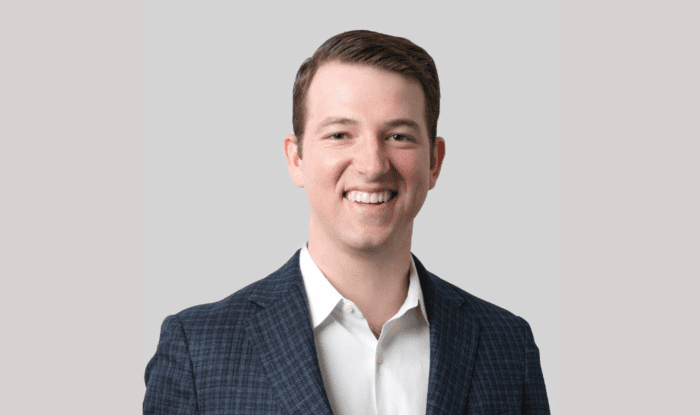 A young, white, professional man with short brown hair smiles into the camera