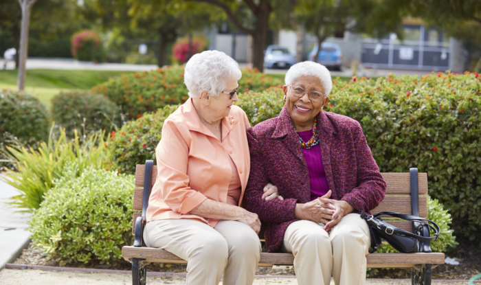 Two women sitting together outside on a bench