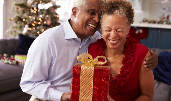 Senior Couple Exchanging Christmas Gifts At Home
