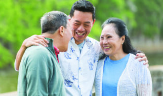 Intergenerational asian family stands together outside.