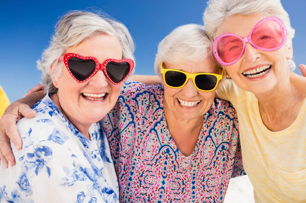 3 elderly ladies wearing sunglasses smile