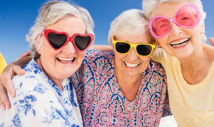 3 elderly ladies wearing sunglasses smile