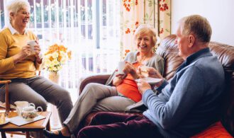 a group of elderly people sits enjoying tea together in their senior living community