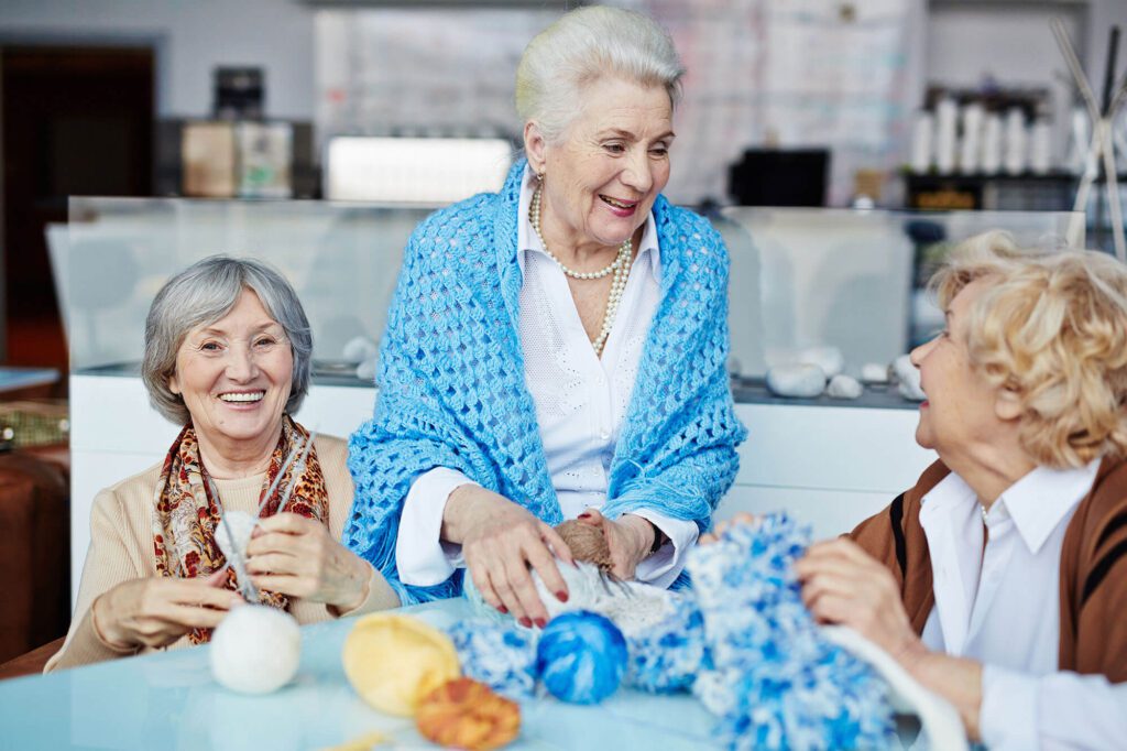 a group of elderly ladies talk about knitting together