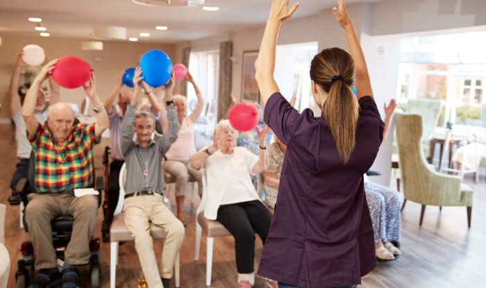 a woman leads a class in movement for a group of seniors