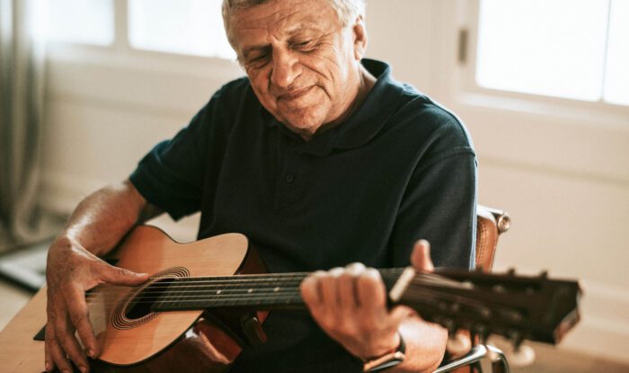 an elderly man plays guitar