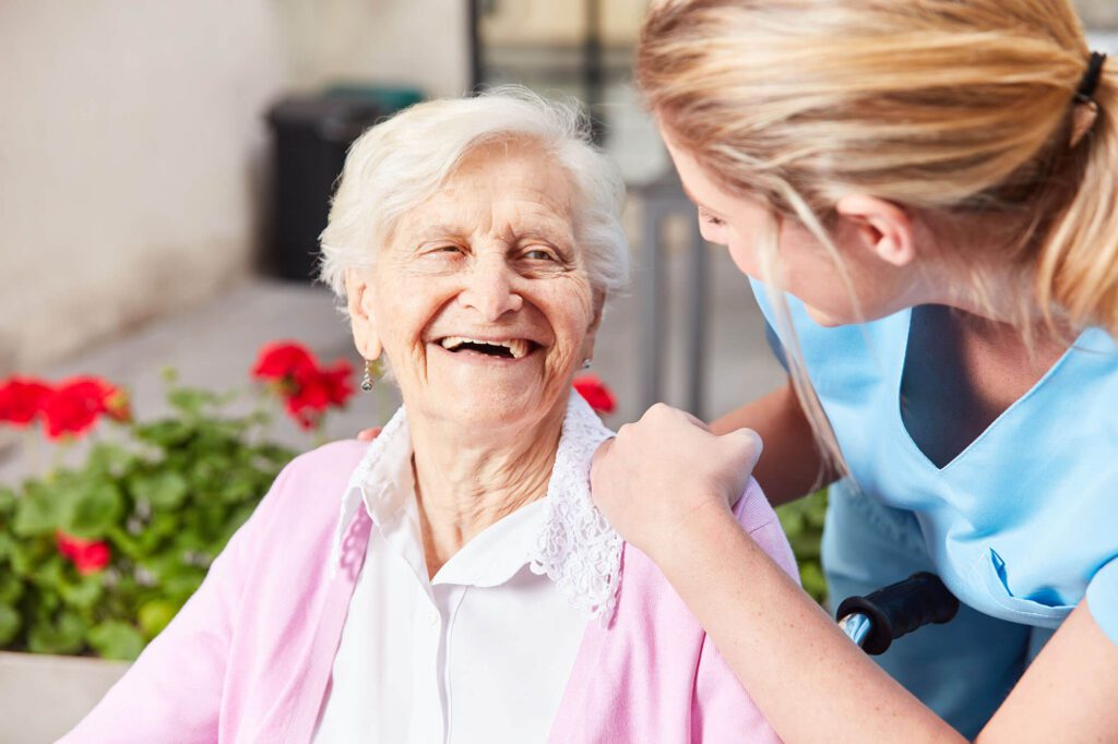 an elderly woman and caretaker share a laugh