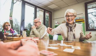 an elderly man and woman playing cards for activity time