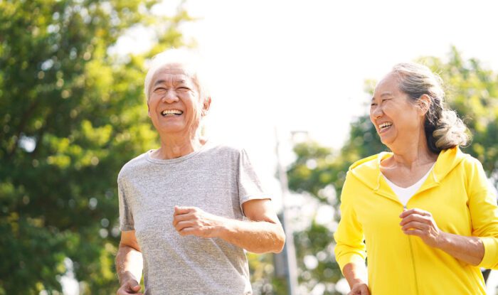 a elderly man and woman go for a run on a sunny day as an activity