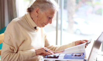 an elderly woman reads a magazine for education