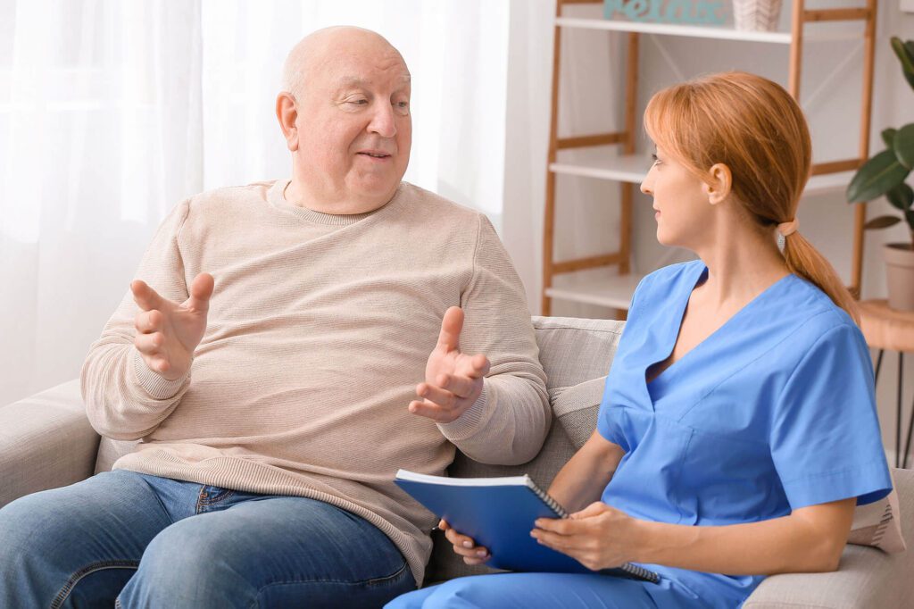 A elderly man has a conversation with a caretaker