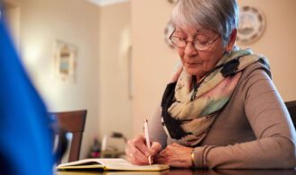 an elderly woman writes in a journal