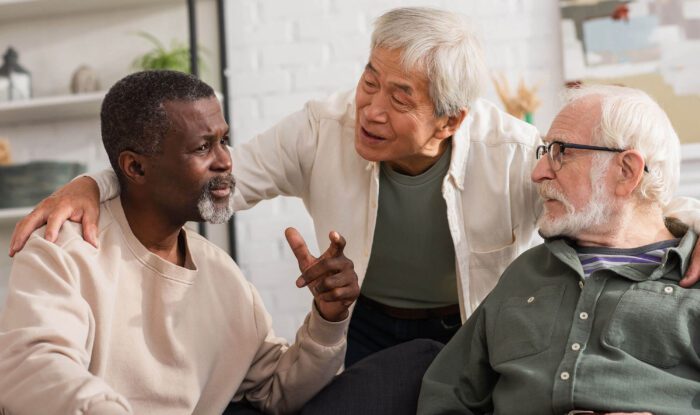 3 elderly men share stories together