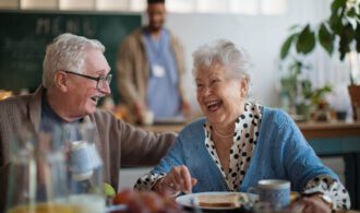 An elderly man and woman share a good laugh over a meal in senior living