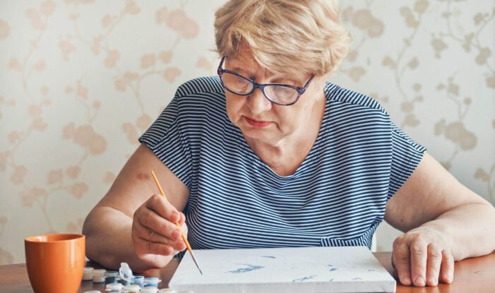 An elderly woman painting Senior - Generations LLC