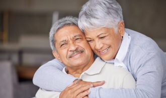 an elderly couple share a hug and a smile