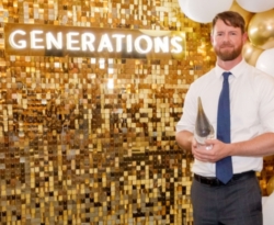 Man stands in front of a gold backdrop and accepts an award