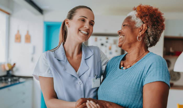 An elderly woman smiles at her assisted living assistant