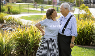 A couple stands in the gardens at Paradise Village Assisted Living in Southern California