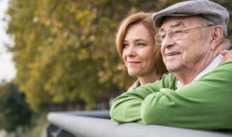 An elderly man and woman stare out a scenic vista
